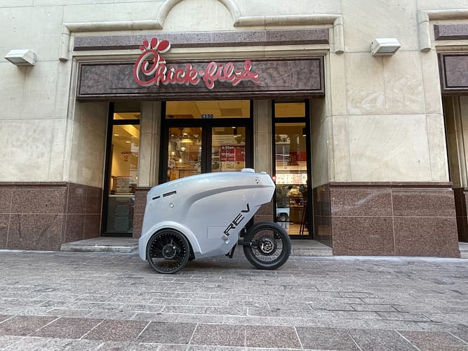 Refraction AI delivery robot in front of Chick-fil-A in Austin