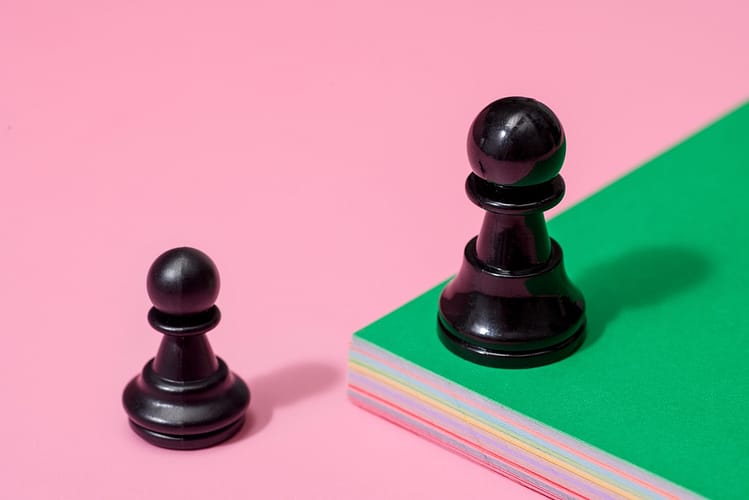 one chess pawn on a green elevated platform, with one on lower pink platform. startups and Market downturns