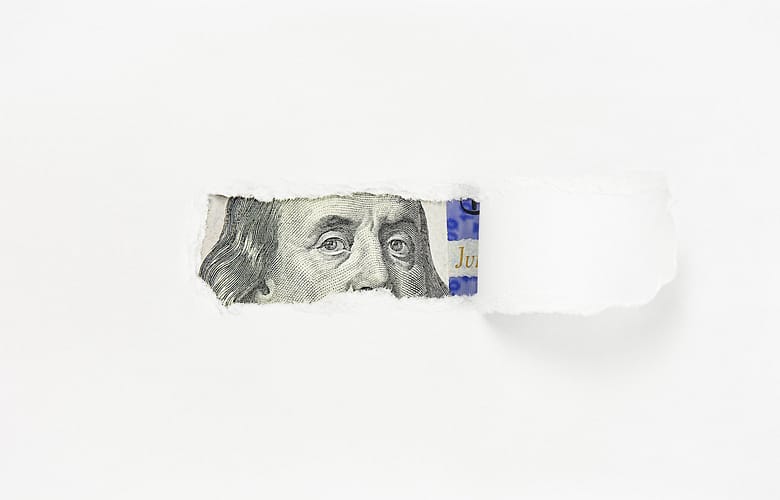 Benjamin Franklin portrait on one hundred dollar bill in torn paper hole, close-up