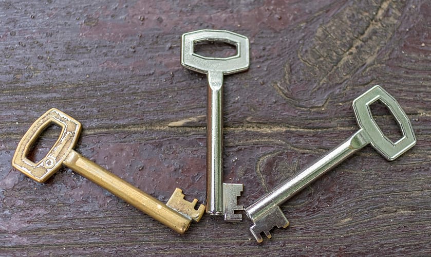 Three antique silver and gold-plated keys