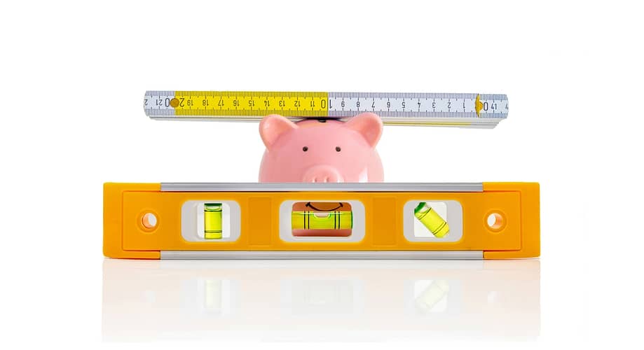 Piggy bank with folding rule and spirit level against a white background